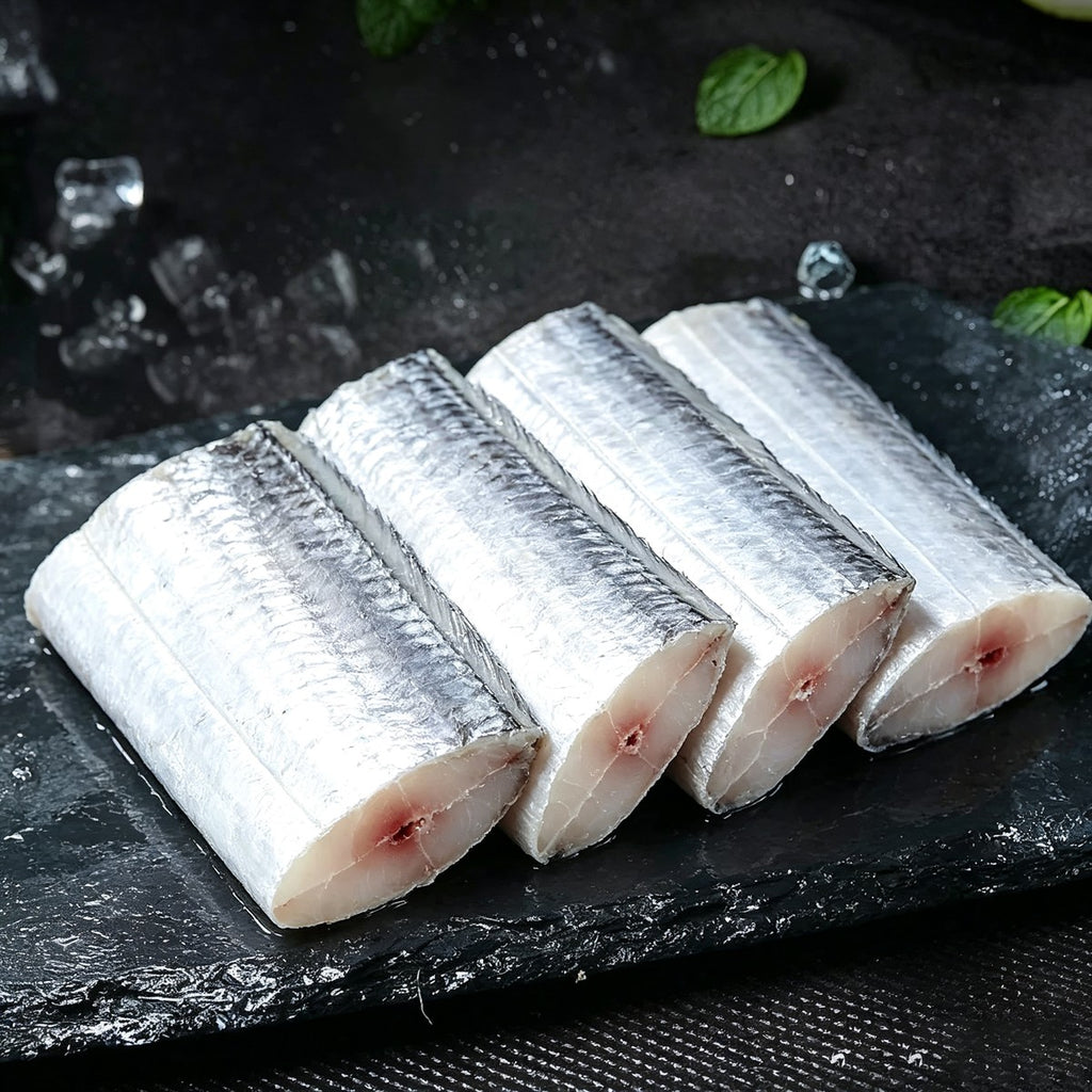 Three frozen beltfish cut sections on dark slate with ice and mint