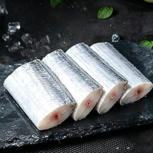 Three frozen beltfish cut sections on dark slate with ice and mint