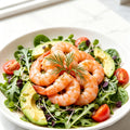 Sweet shrimp arranged on a green salad with avocado and tomato